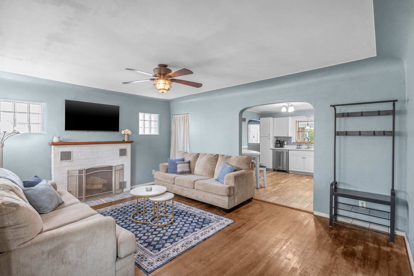 Living room seen from the fireplace side, with an arched doorway through to the kitchen and a coat rack by the door