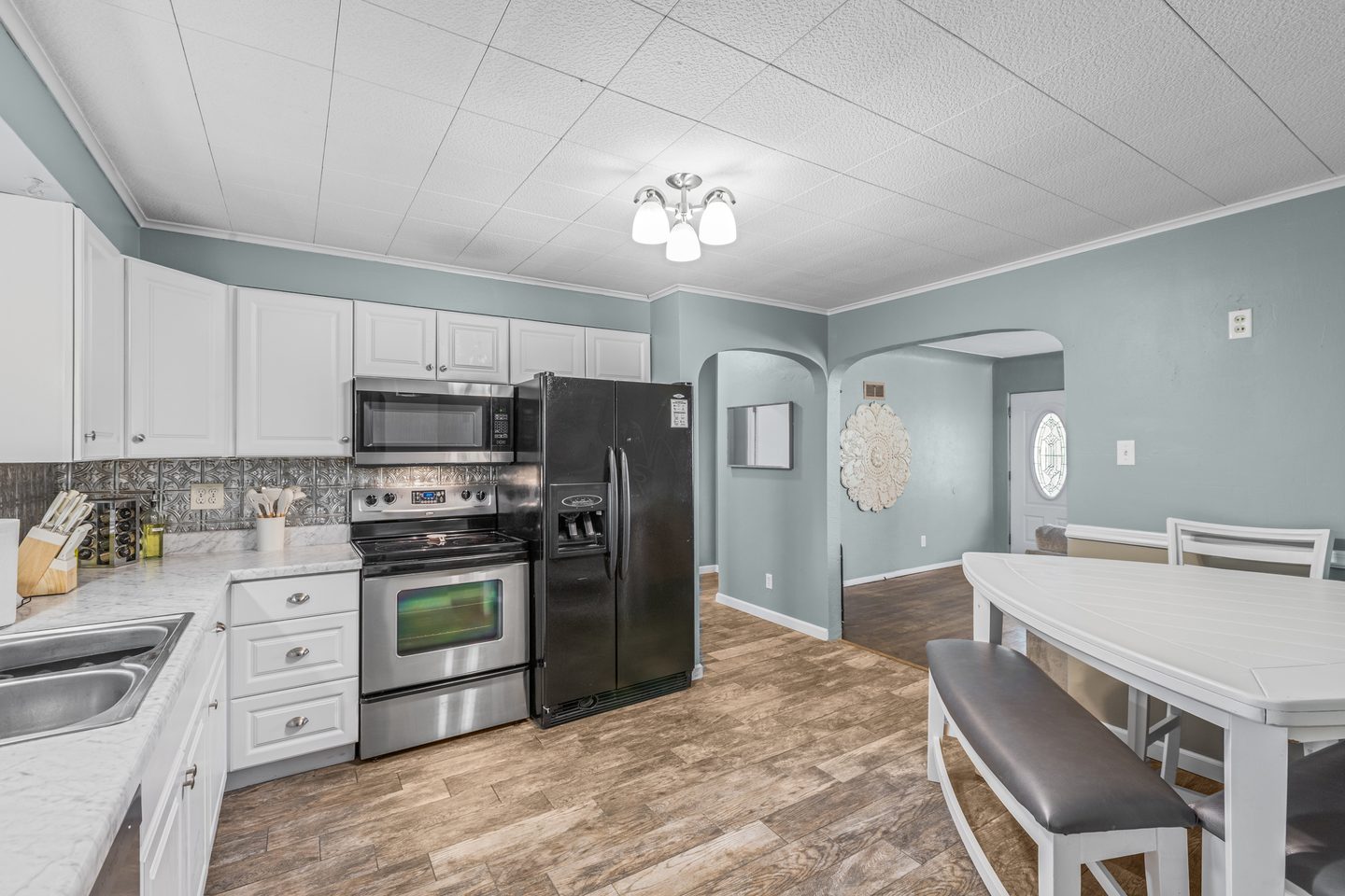 Kitchen with white cabinets, a stainless microwave and range, a black refrigerator and an arched doorway
