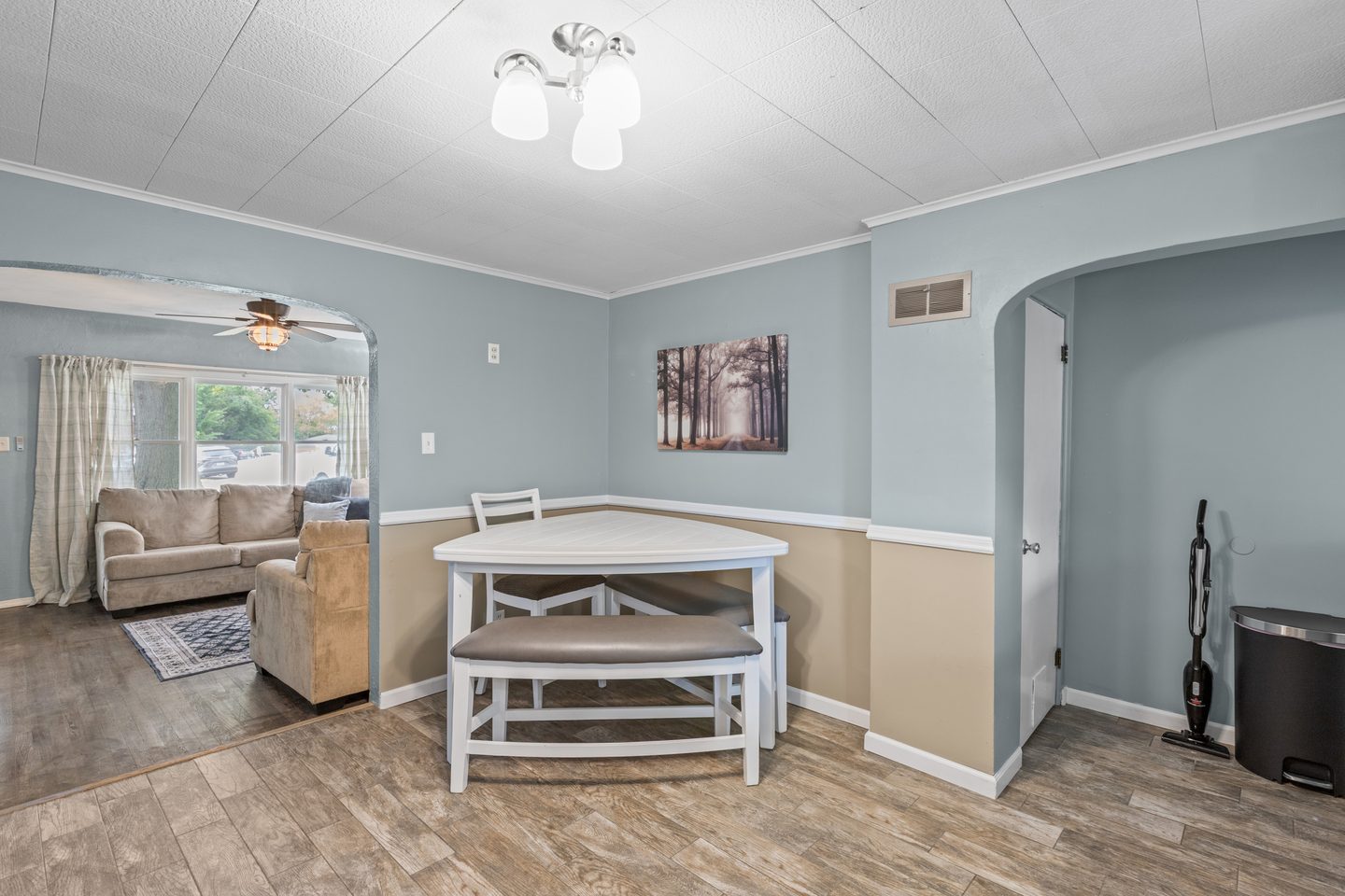 Dining table with a bench, looking through an arched doorway to the living room