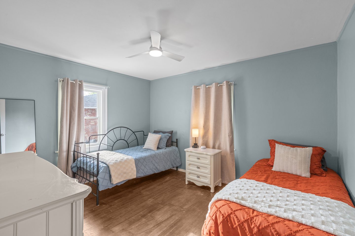 Bedroom with a daybed and a twin bed in orange bedding, a dresser and a nightstand