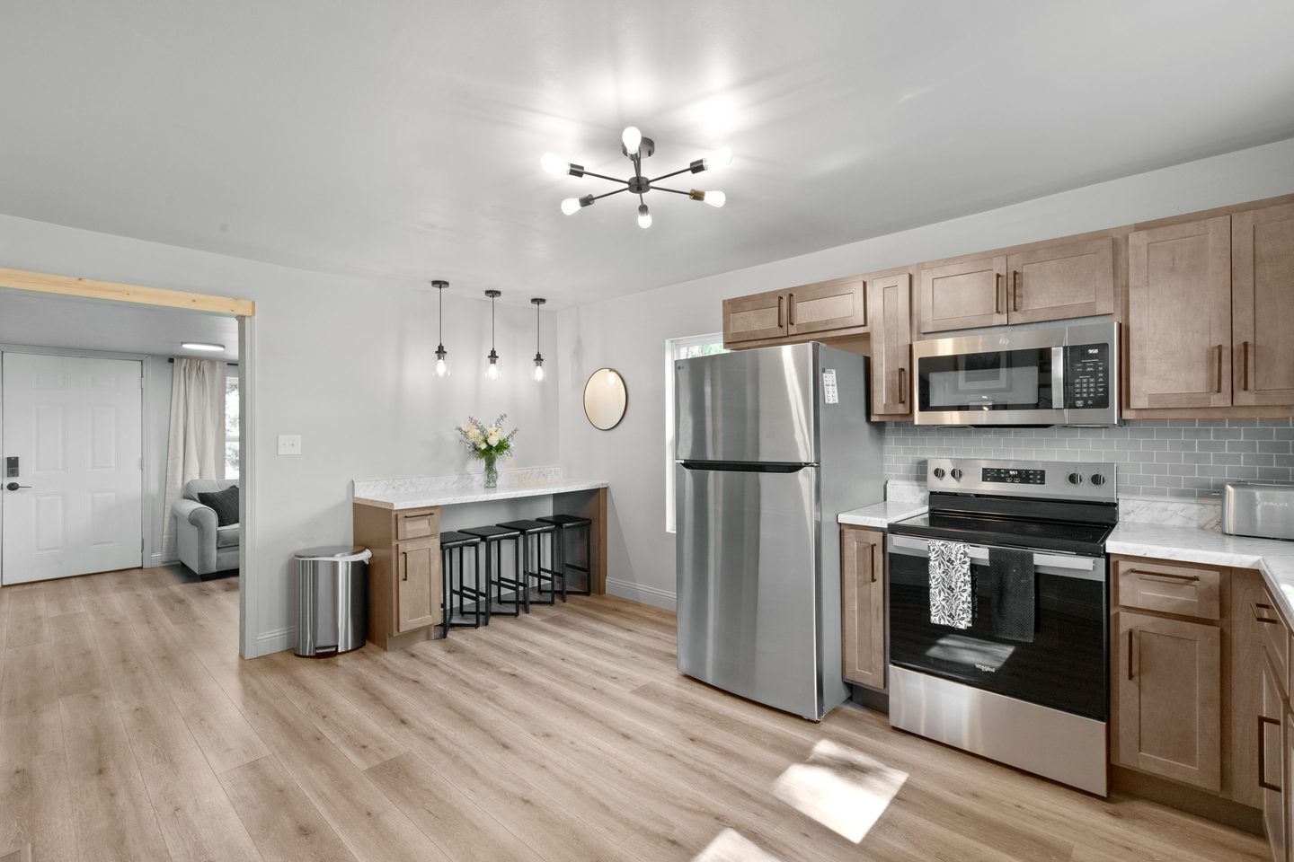 Kitchen with light wood cabinets, white counters, pendant lights, a breakfast bar and stainless appliances