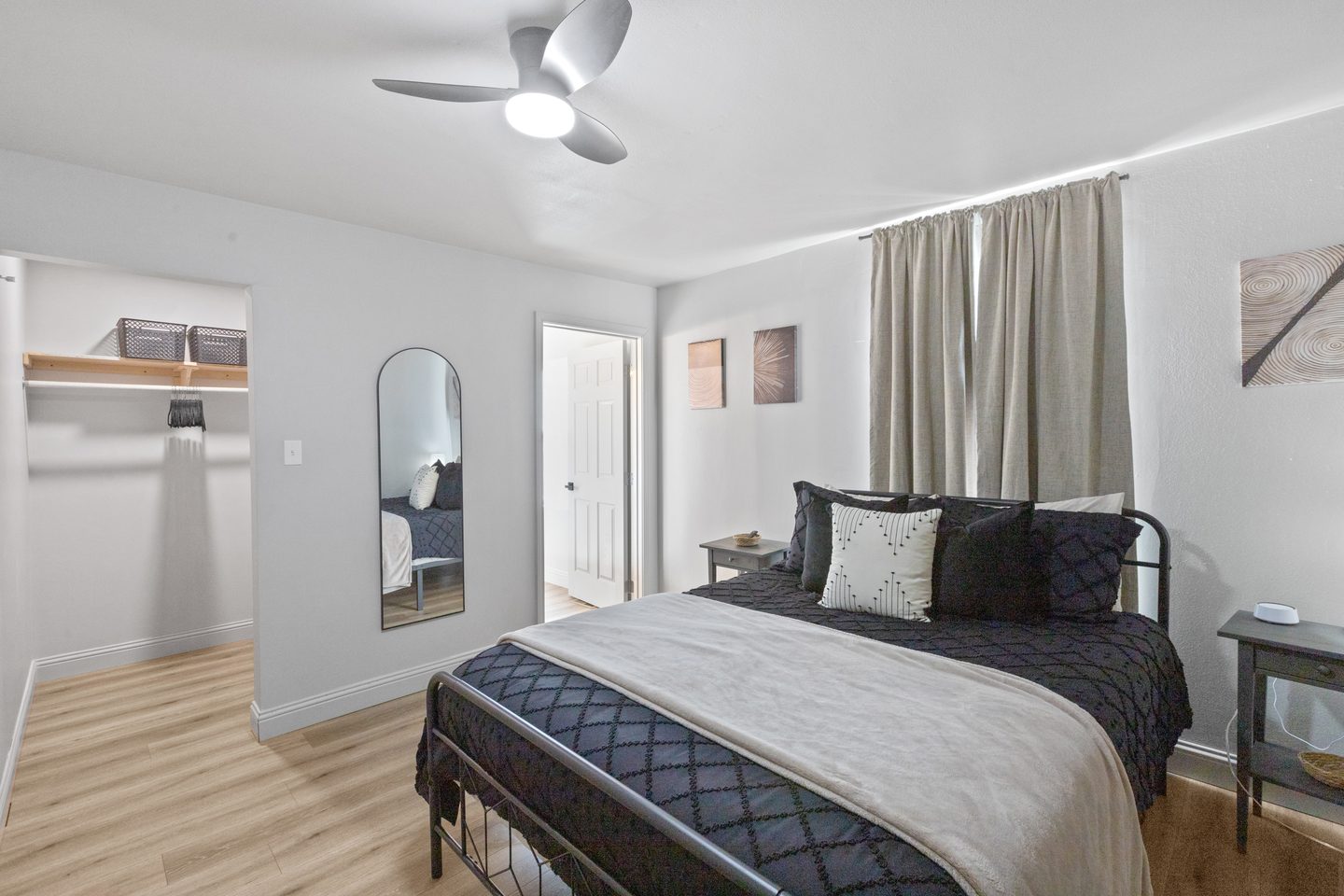 Bedroom with a queen bed in navy bedding, a black metal frame, a walk-in closet and a door to its own bathroom