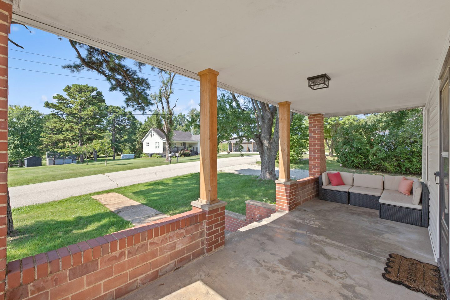 Covered front porch with brick half-walls and an outdoor sectional sofa
