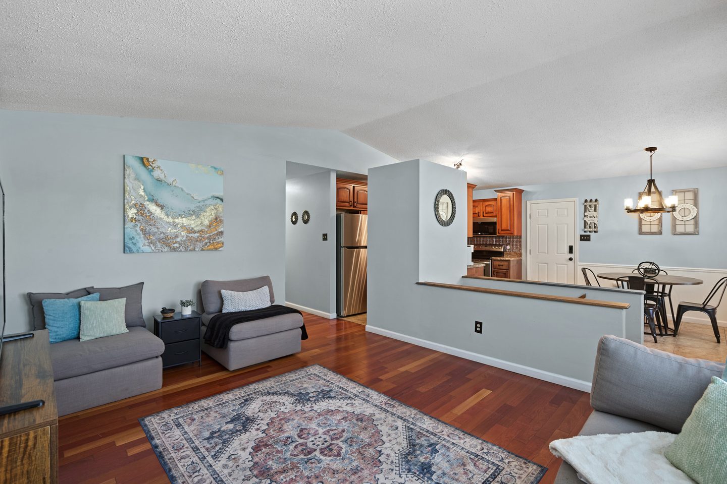 Living room with cherry wood floors and a half wall opening onto the kitchen and dining area