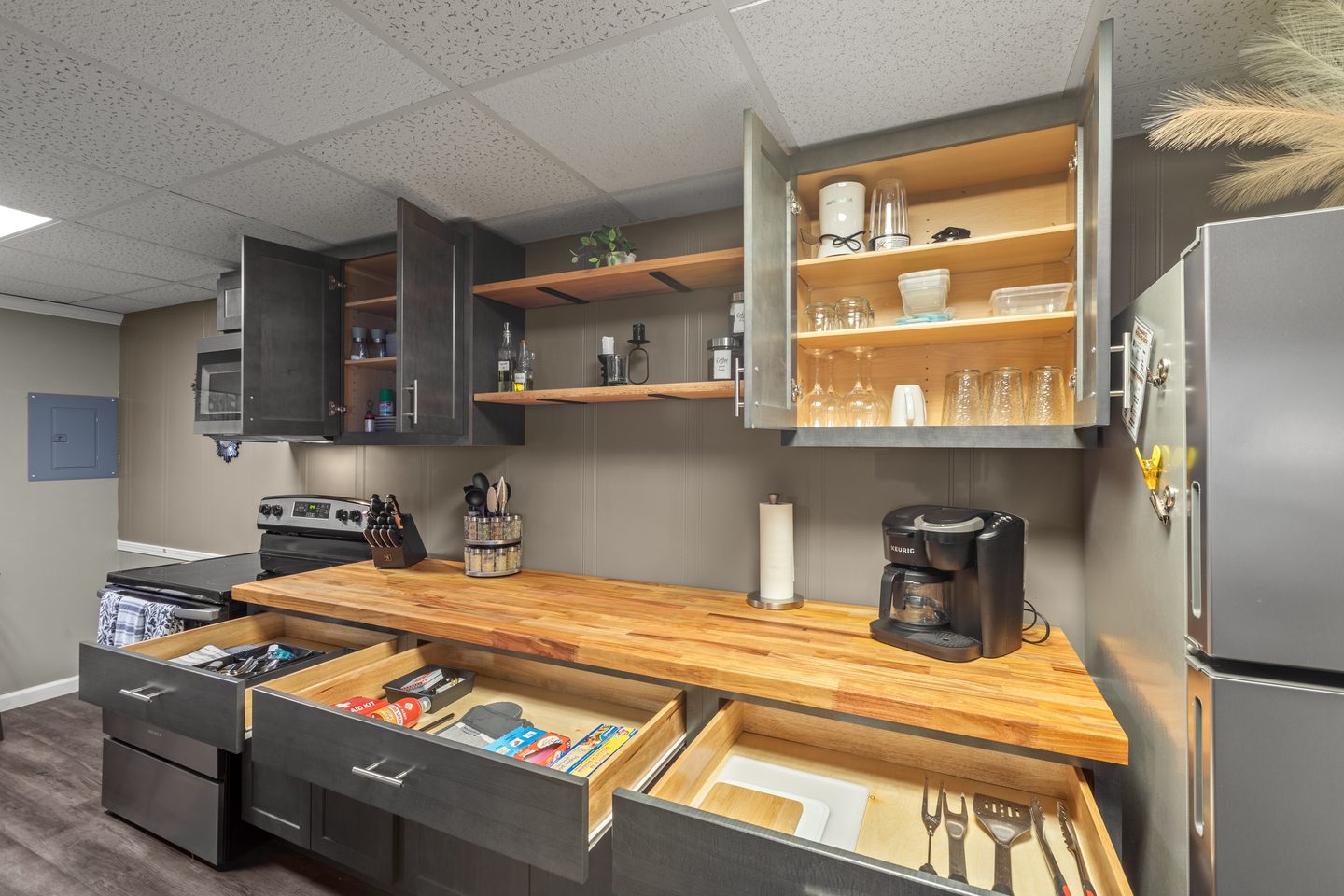 Kitchen cabinets and drawers open to show dishes, glasses, cookware and utensils