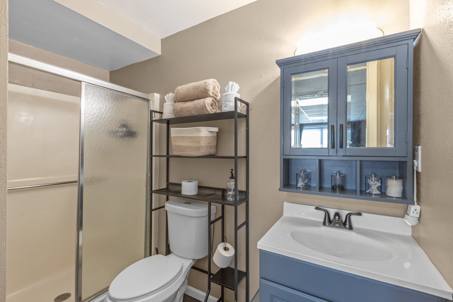 Bathroom with a walk-in shower, a blue vanity with a matching mirror cabinet and a towel rack