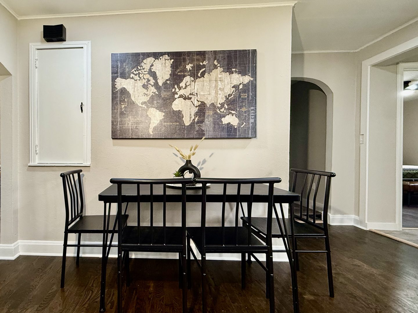 Black dining table with six chairs under a large framed world map