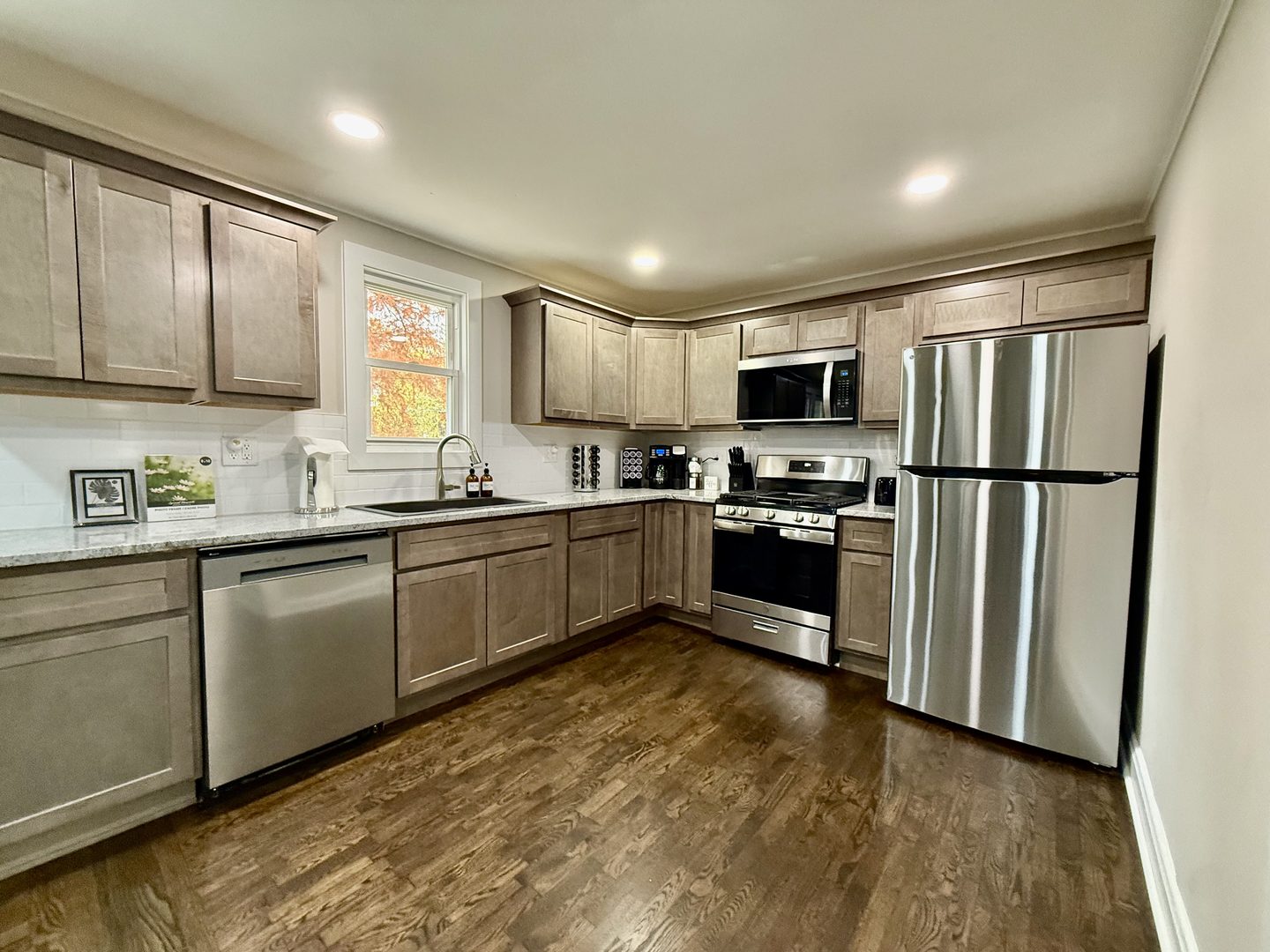 Kitchen with grey shaker cabinets, granite counters, a gas range and a stainless refrigerator and dishwasher