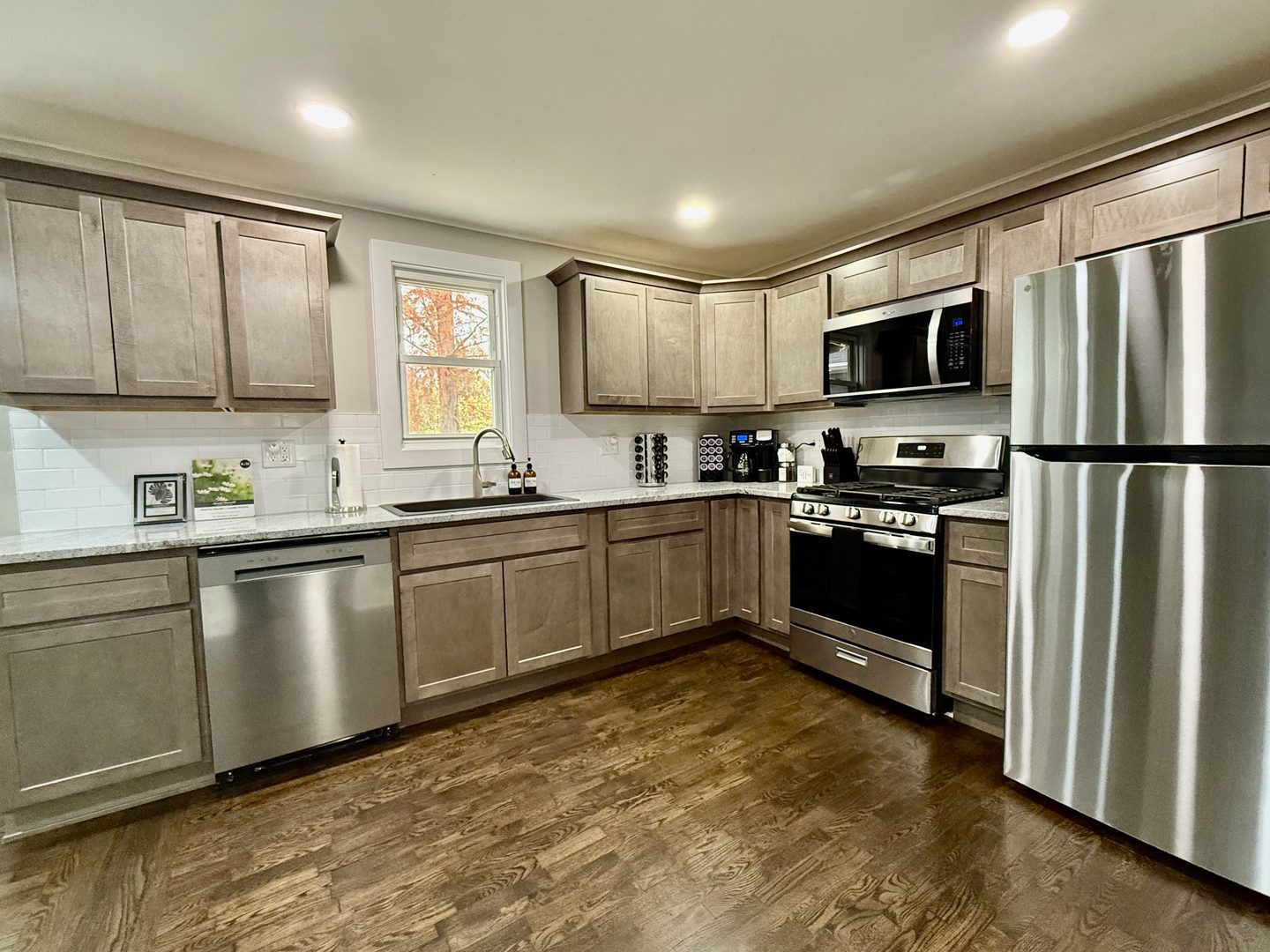 The kitchen from the other end, with stainless appliances and recessed lighting