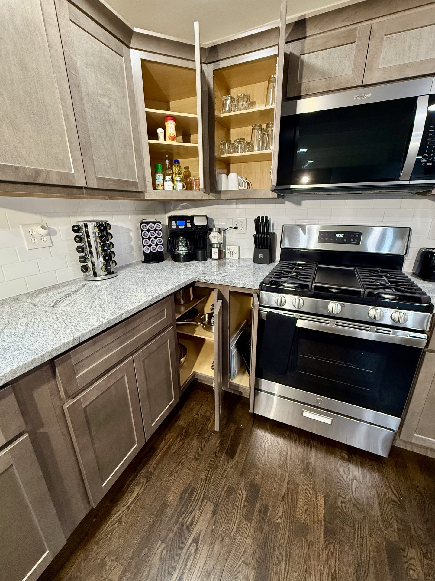 Kitchen corner with open cabinets, a coffee station, a gas range and a microwave