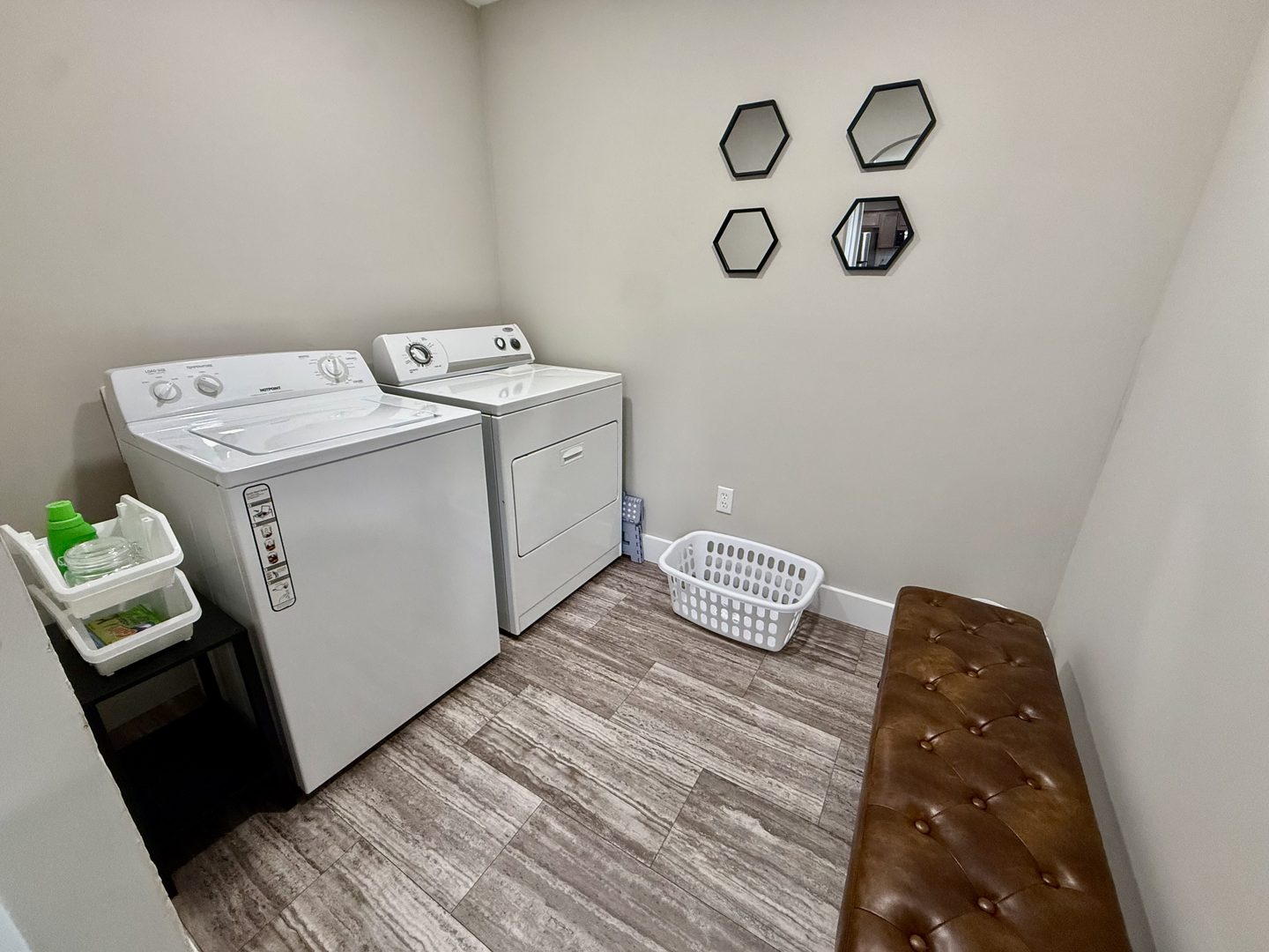 Laundry room with a washer and dryer, a hamper and a leather bench